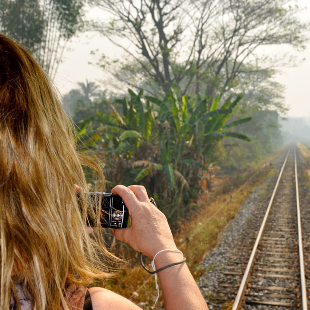 Woman taking photos from the rear lounge on the Kuala Lumpur-Bangkok by Luxury Train journey