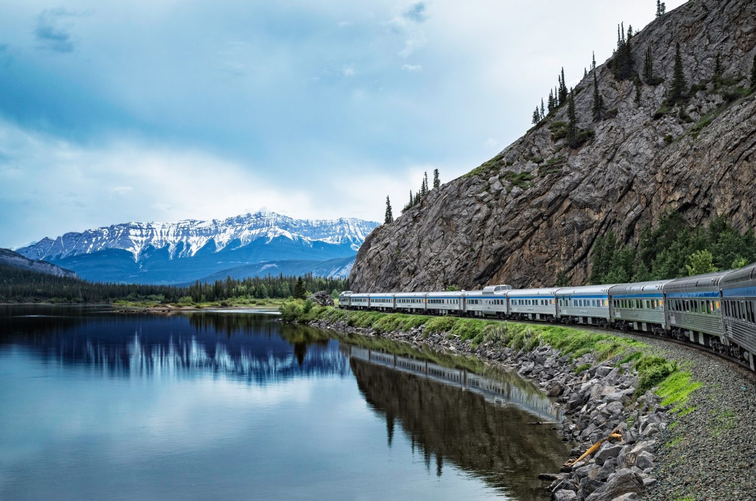 Train passing between a large lake and a mountain