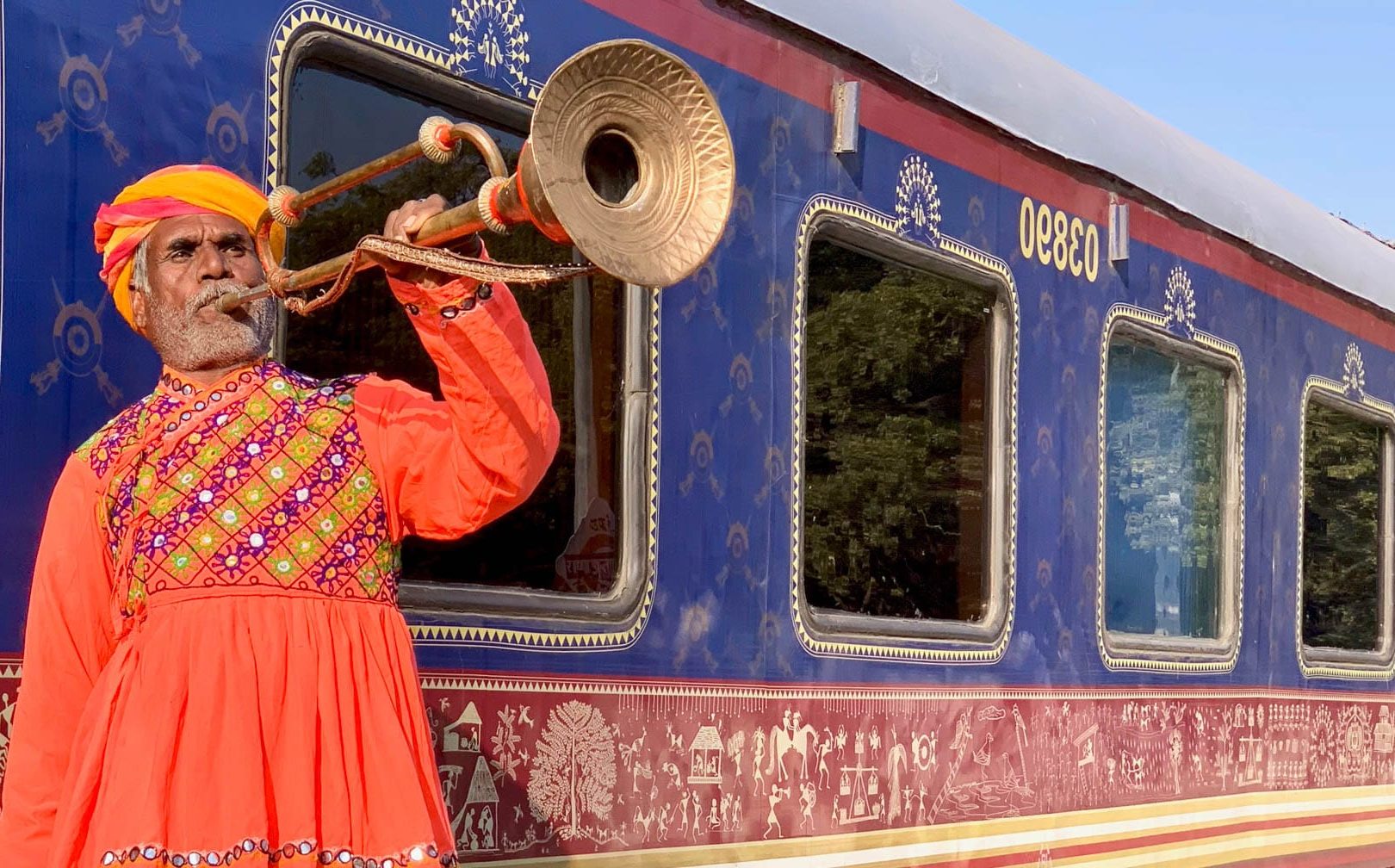 Man playing an instrument by the Deccan Odyssey train