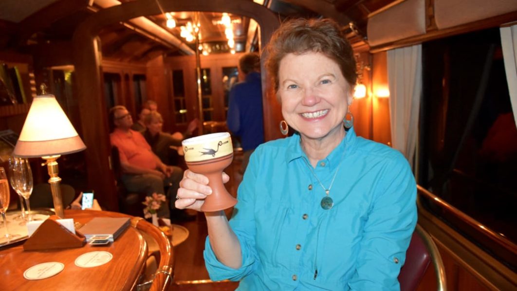 Female guest holding a drink on the Belmond Hiram Bingham train